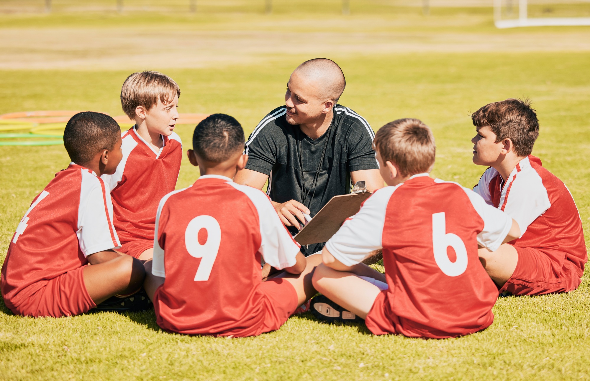 kids, soccer and team coach planning training with clipboard on soccer field for sport competitiion
